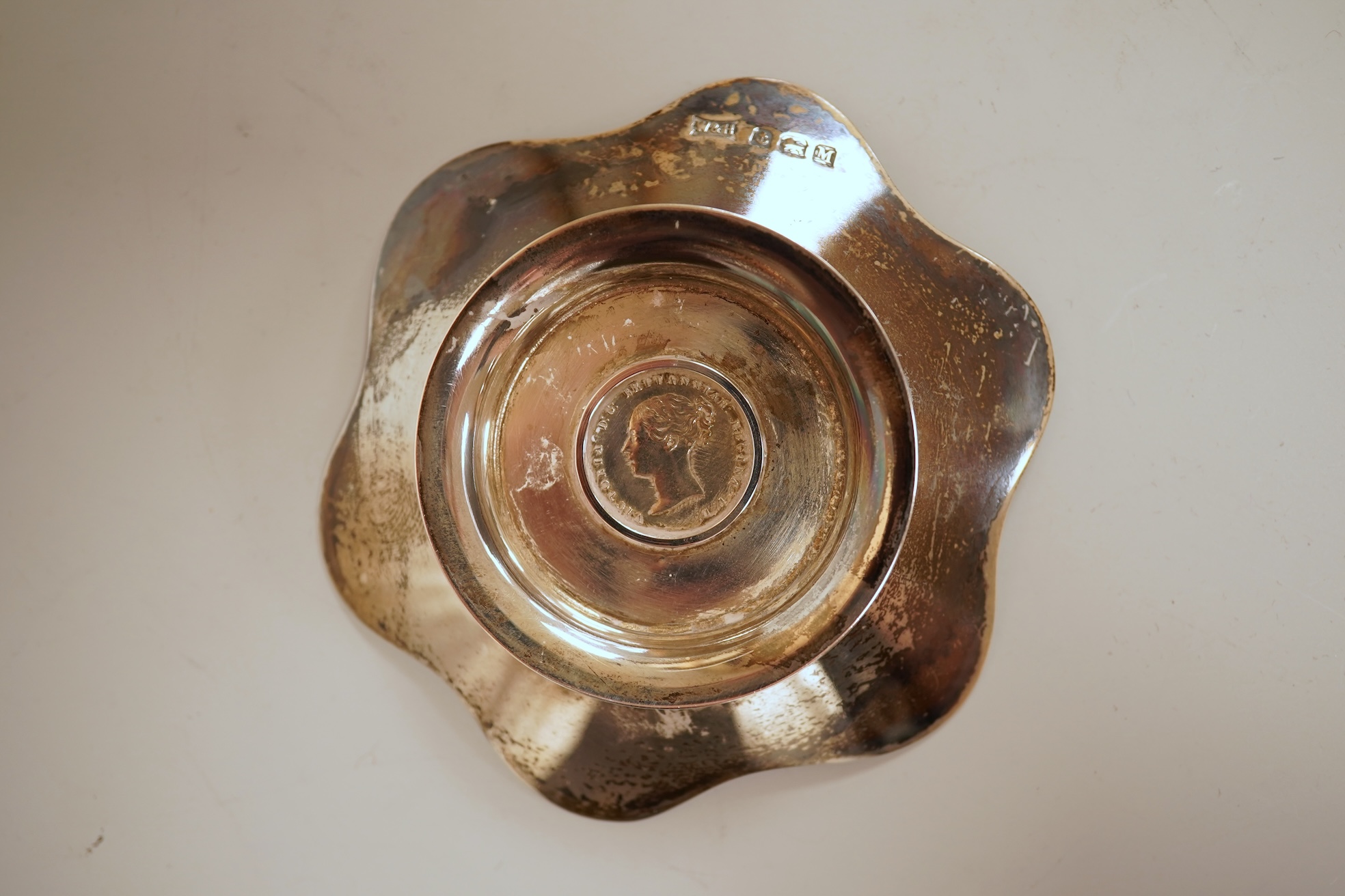 A cased set of four George V silver flower head shaped nut dishes, each inset with an 1850 maundy coin, Walker & Hall, Birmingham, 1936, diameter 77mm.